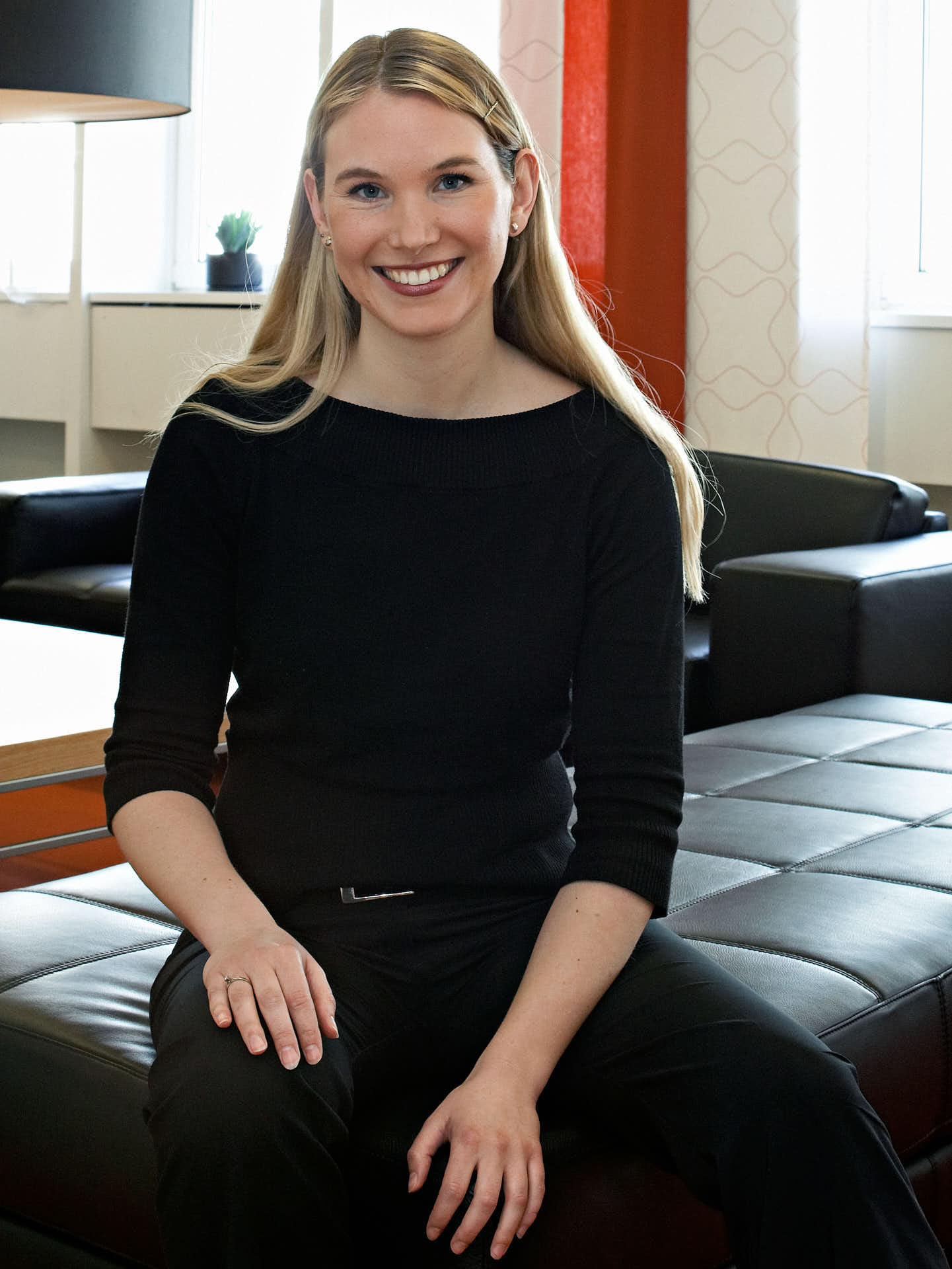 Solna Business Centre kundvärd i företagshotell, leende blond kvinna i svart blus sittande ledigt i lounge. Foto Martin Ekwall.