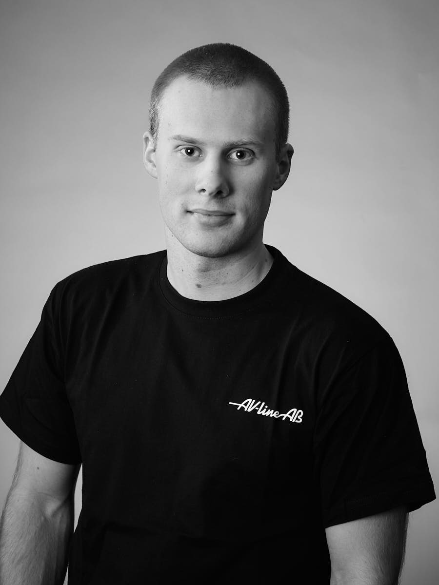 AV-Line porträtt av medarbetare i svart t-shirt mot grå bakgrund