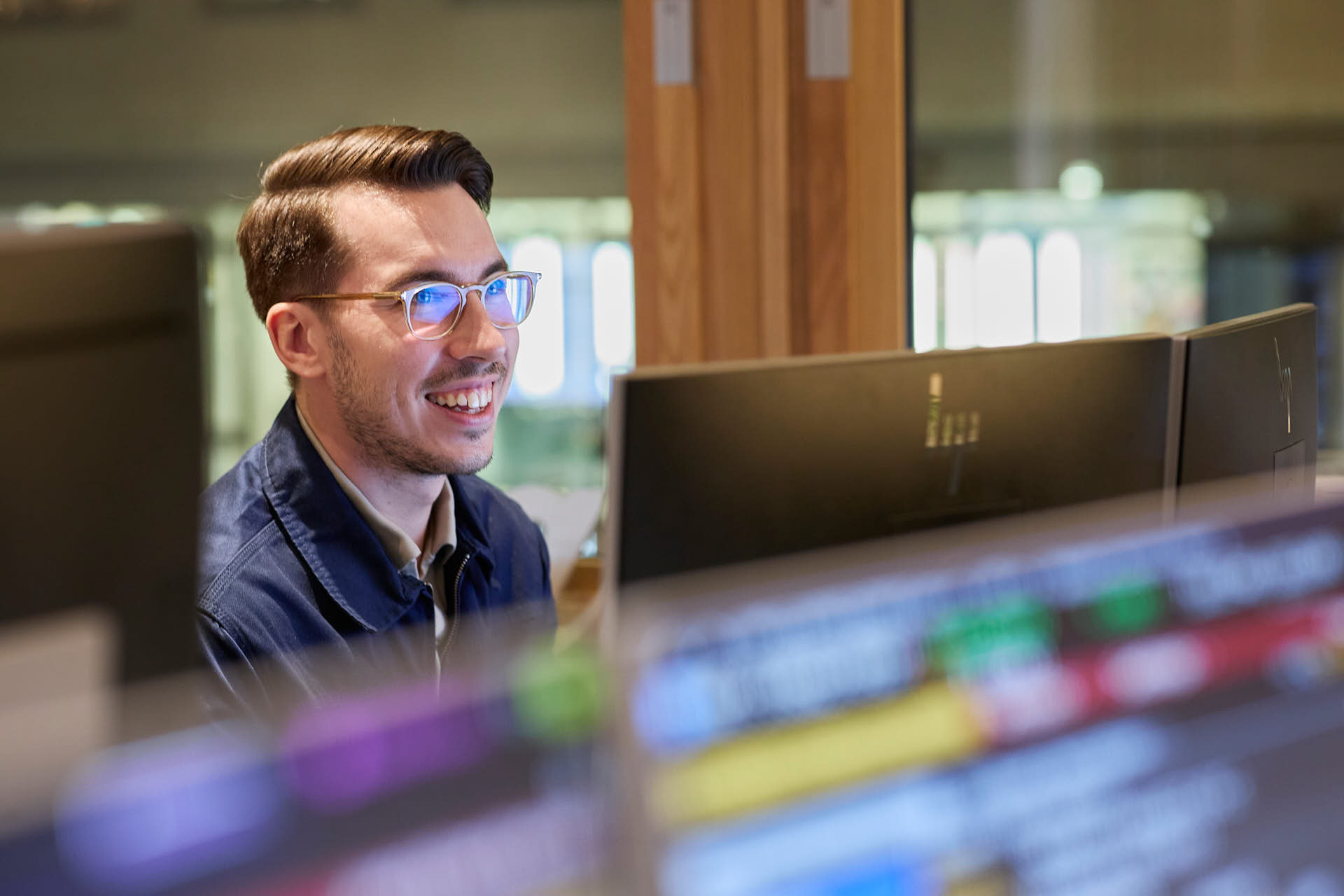 Cae Kapitalförvaltning, Oscar Andrassy tittar på datorskärm, glad, aktieindex suddigt i förgrunden. Fotograferat av Martin Ekwall.