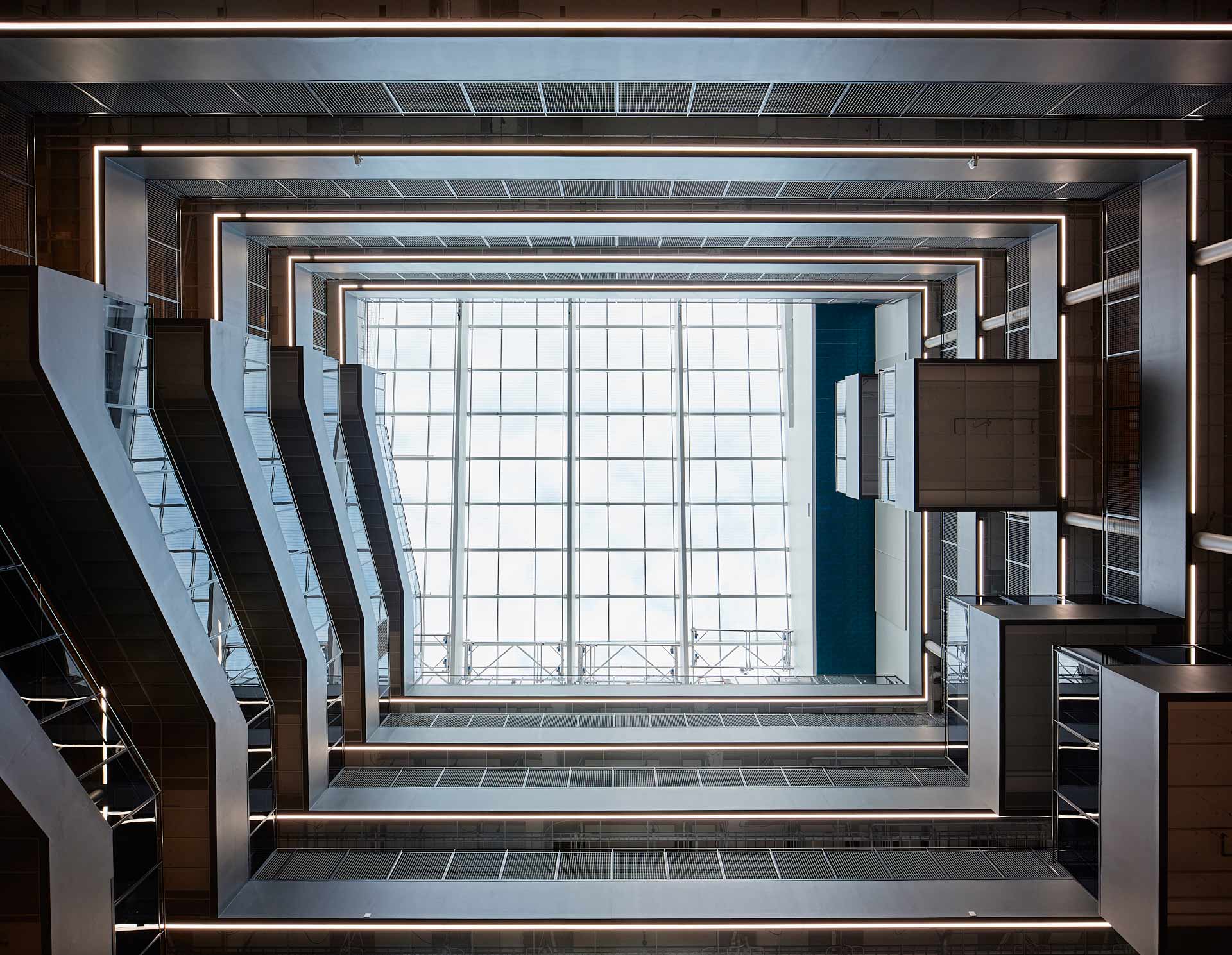 Vy rakt upp i Tele2-husets ljusgård med våningsplan och linjära ljuslister runt öppningen, projektlett av In3prenör. Foto Martin Ekwall.