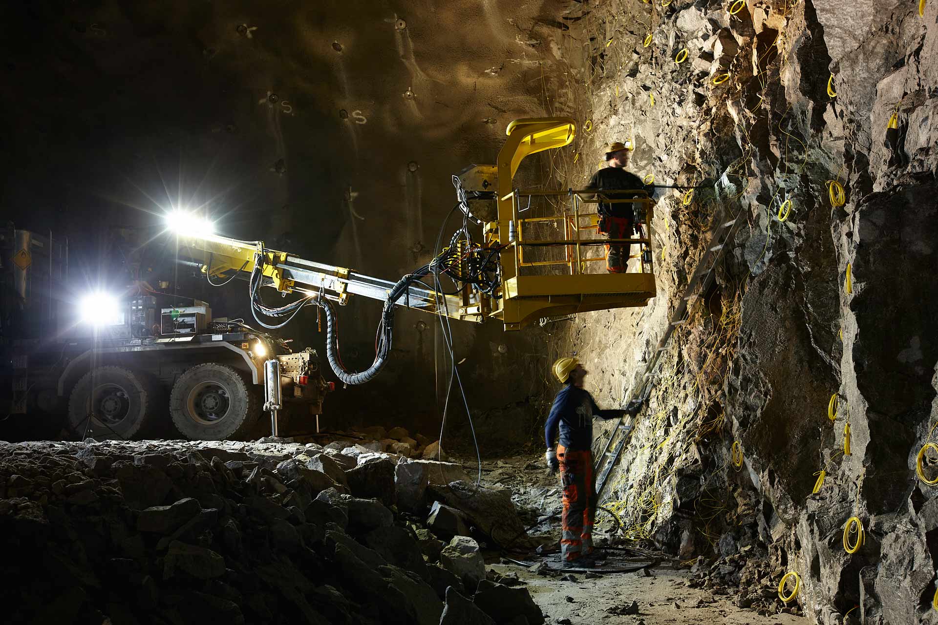 Spränginstallation i tunnel vid Norra Länken med kranarm och Ramirents elförsörjning, montör vid bergväggen. Foto Martin Ekwall.