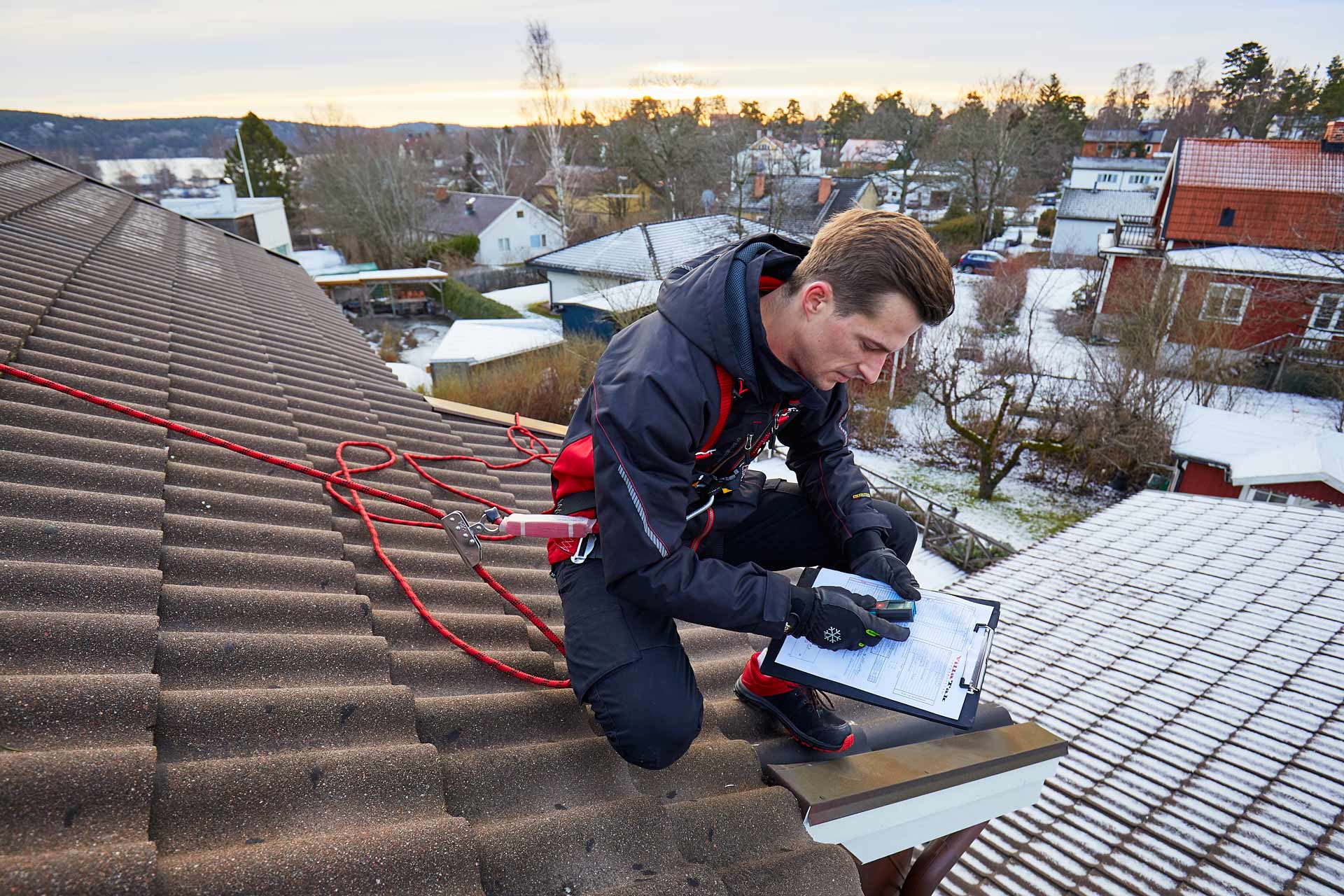 Offerträknare noterar mått och iakttagelser vid takkant på clipboard under takinspektion. Foto Martin Ekwall.