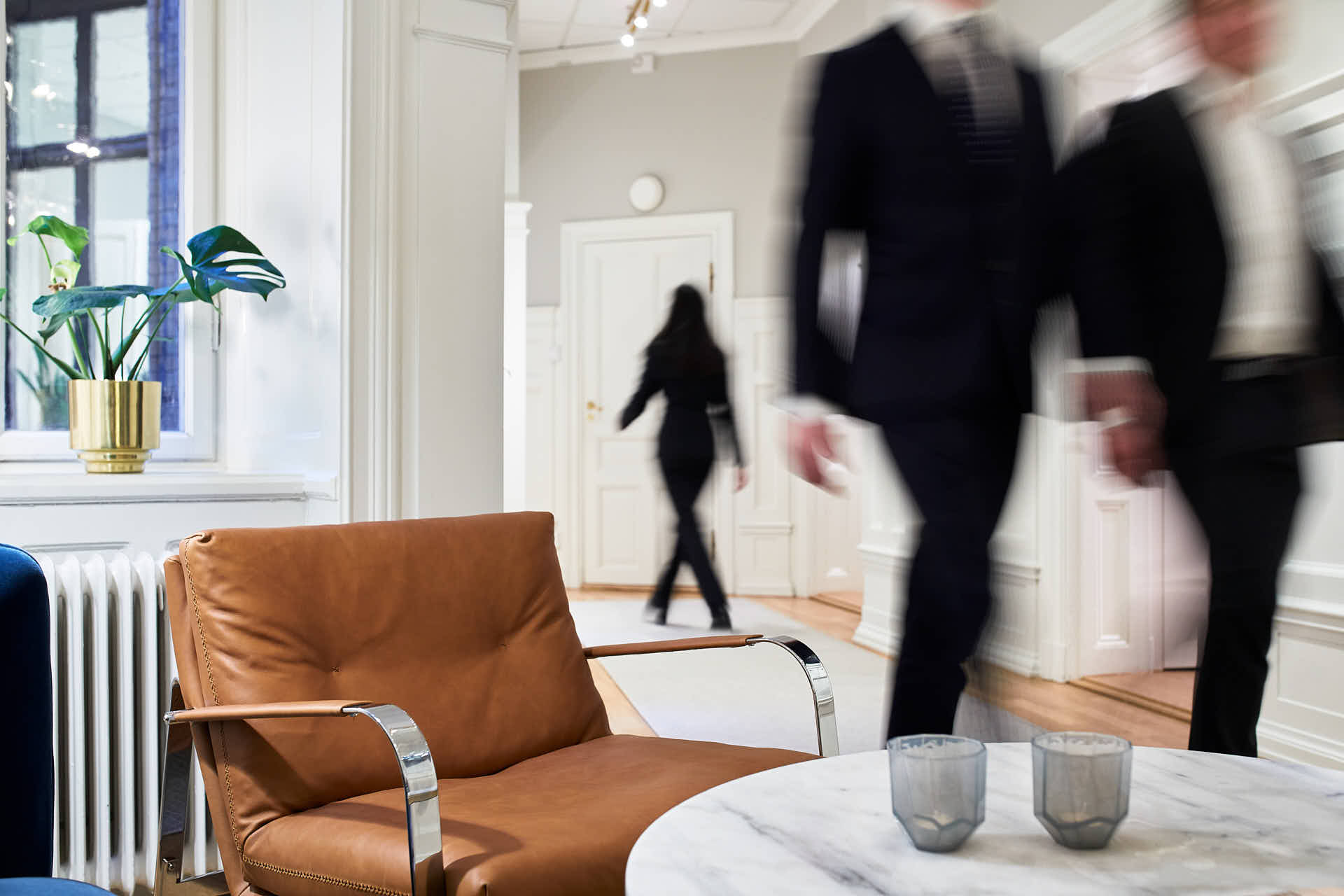 Tre människor möter varandra i rörelse i en korridor på ett investeringsbolag, Stockholm, foto Martin Ekwall.
