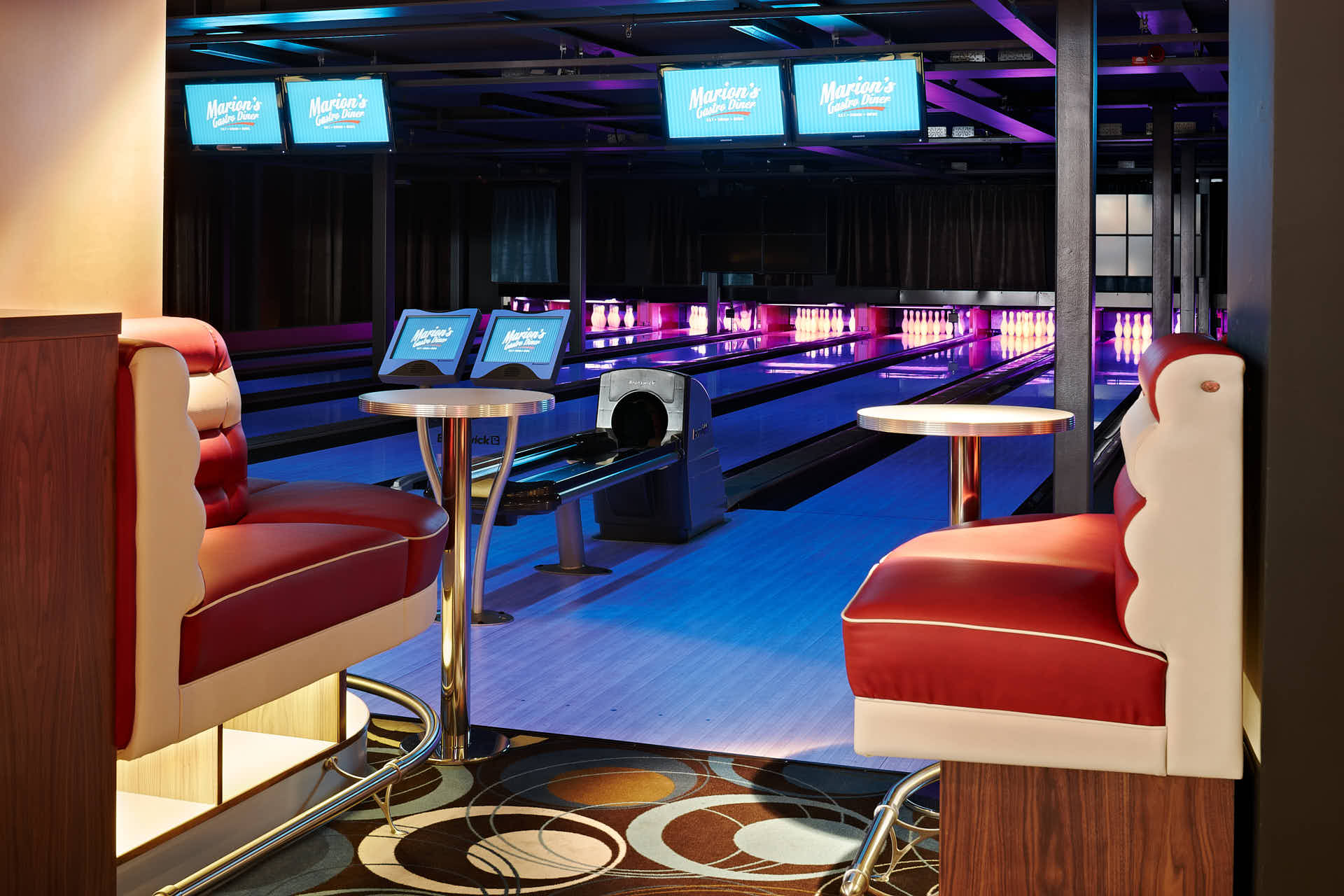 Upplysta bowlingbanor med blågrönt ljus och stoppade sittplatser i förgrunden. Marions Gastro interiörfotograferad av Martin Ekwall för Co-Pilot..