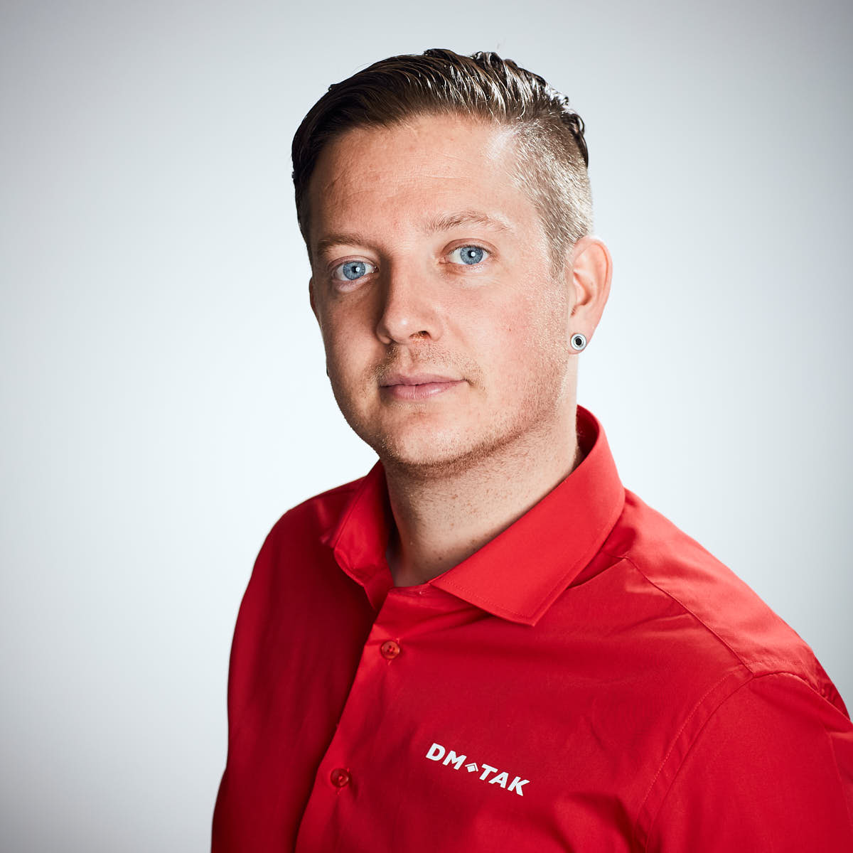 Porträtt av medarbetare på DM TAK, Kristoffer Helander  i röda profilkläder. Foto Martin Ekwall