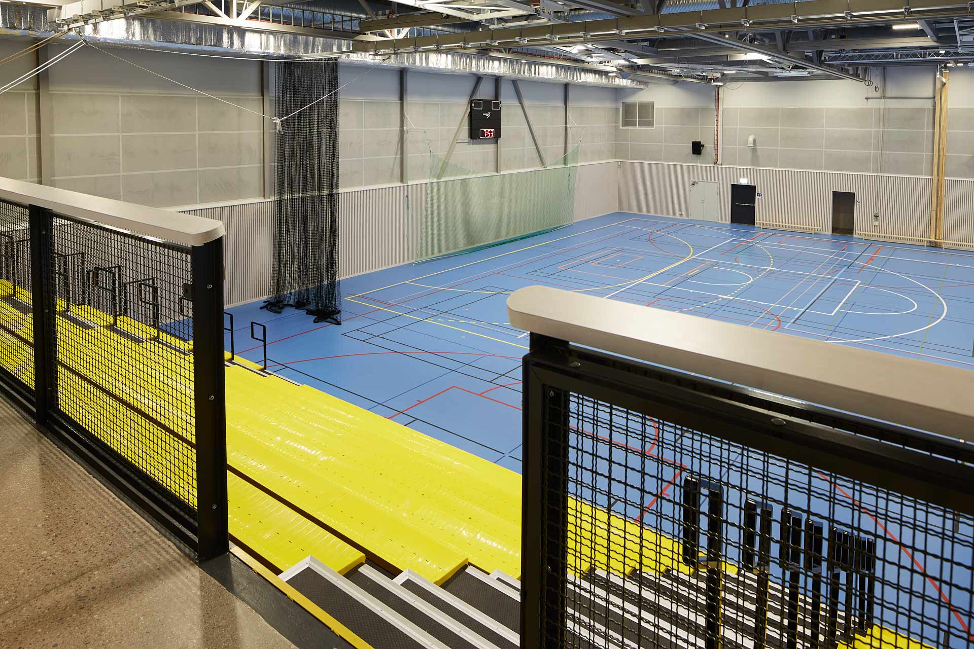 Ekebyhovs sporthall på Ekerö: läktare och sporthall sedd ovanifrån med planmarkeringar på golvet. Byggd av In3prenör, ritad av Comarc Arkitekter. Foto Martin Ekwall.