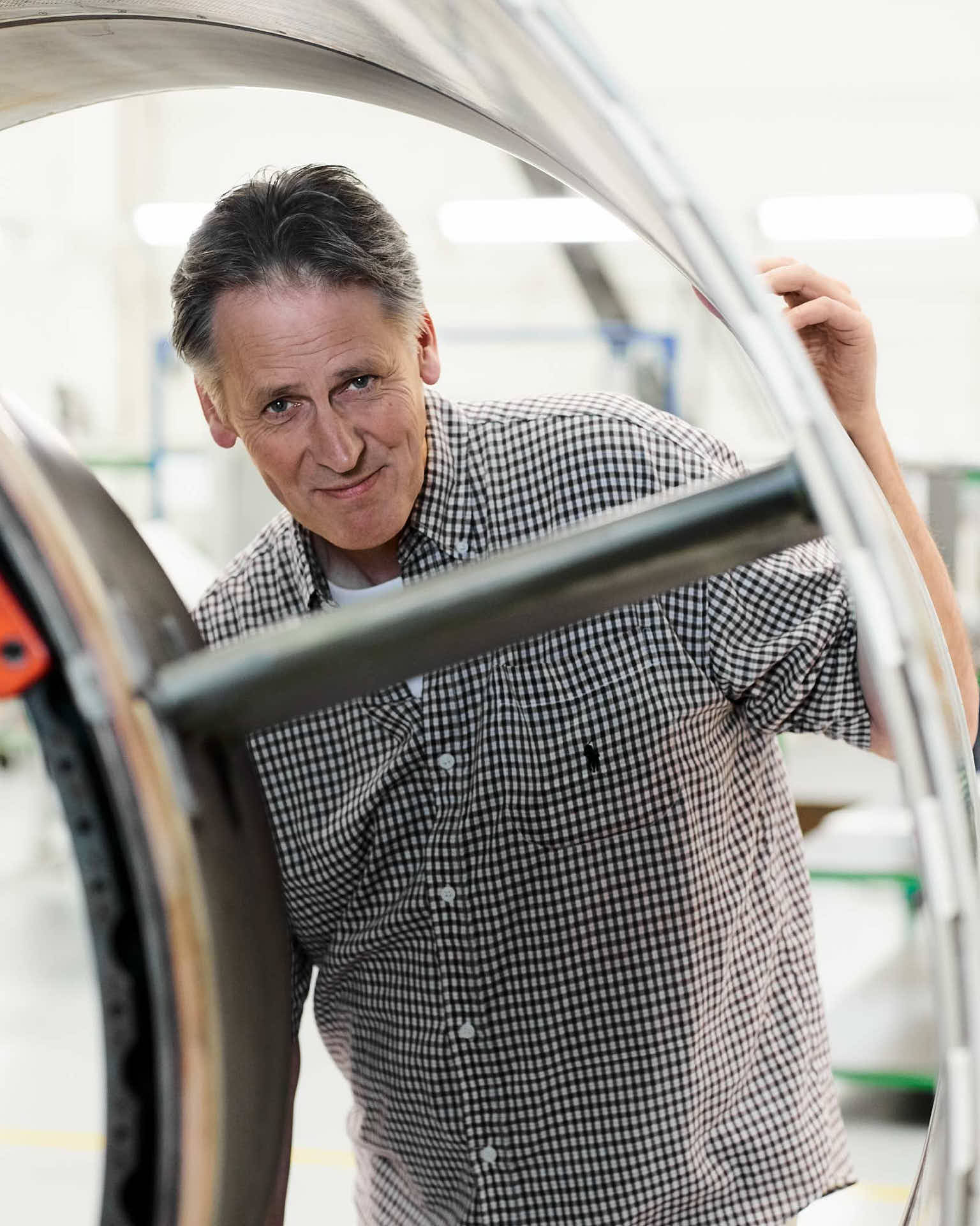 Kundcase för JJ-Gruppen tidningen ABUS Lyftet hos ST Engineering Aerospace – porträtt av Per-Åke Romberg, production manager, stående vid en flygkomponent. Foto Martin Ekwall.