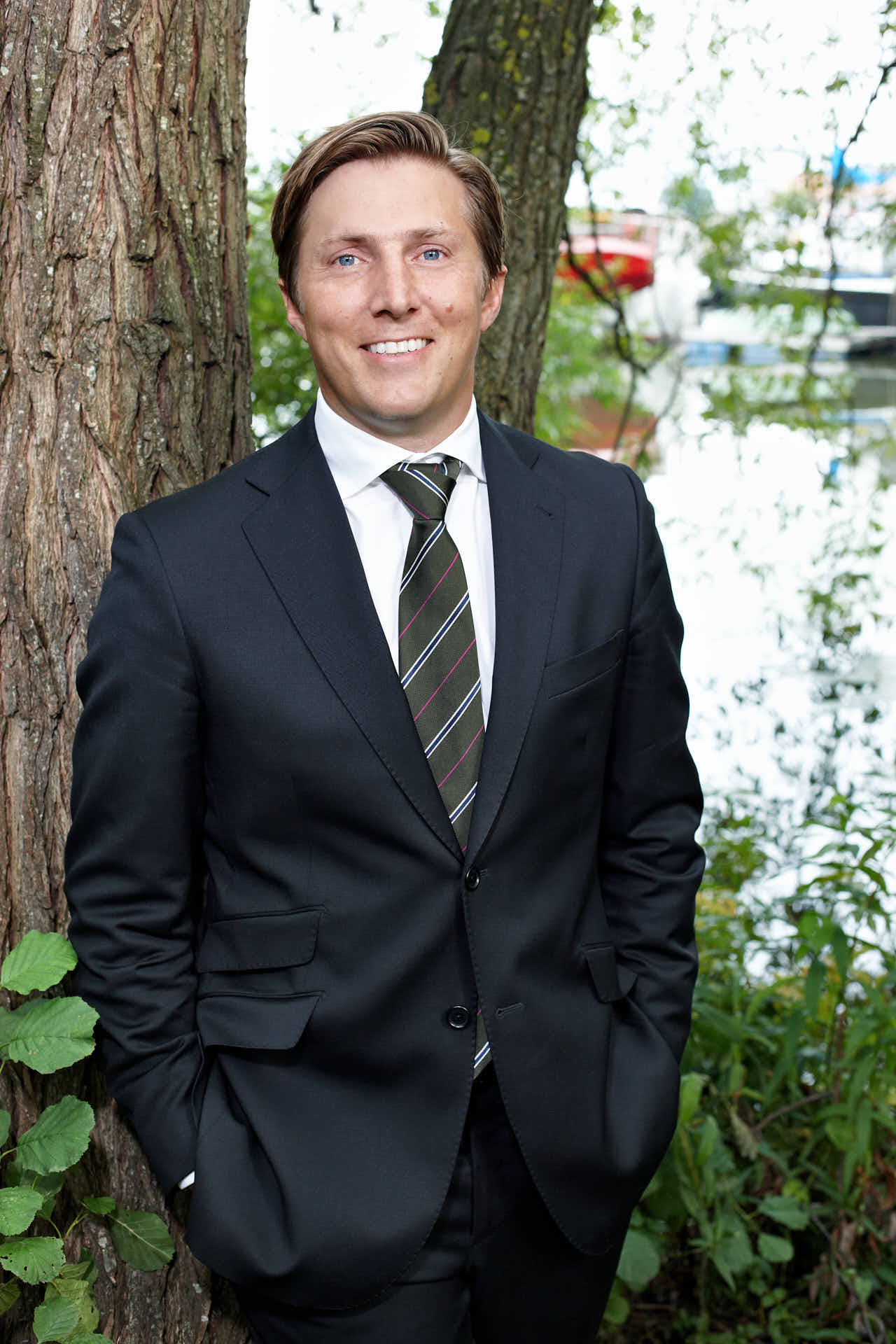 Porträtt av tidigare vd Fredrik Ruben från 3L Systems. Leende i kostym vid träd och vatten. Fotograferat av Martin Ekwall.