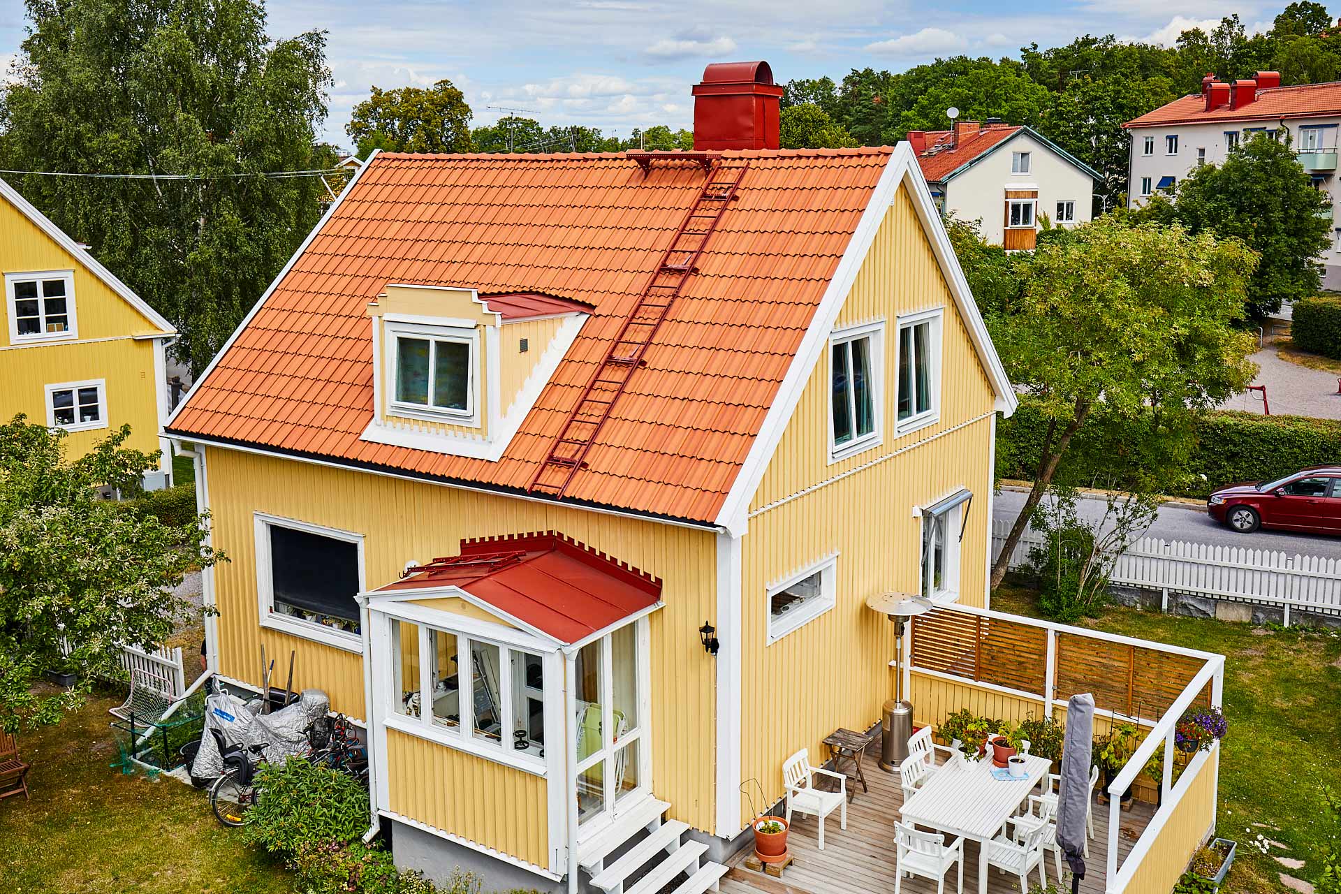 Villa i Bromma med lertegeltak och röda plåtdetaljer på skorsten och takkupor, utfört av Villatakspecialisten. Foto Martin Ekwall.