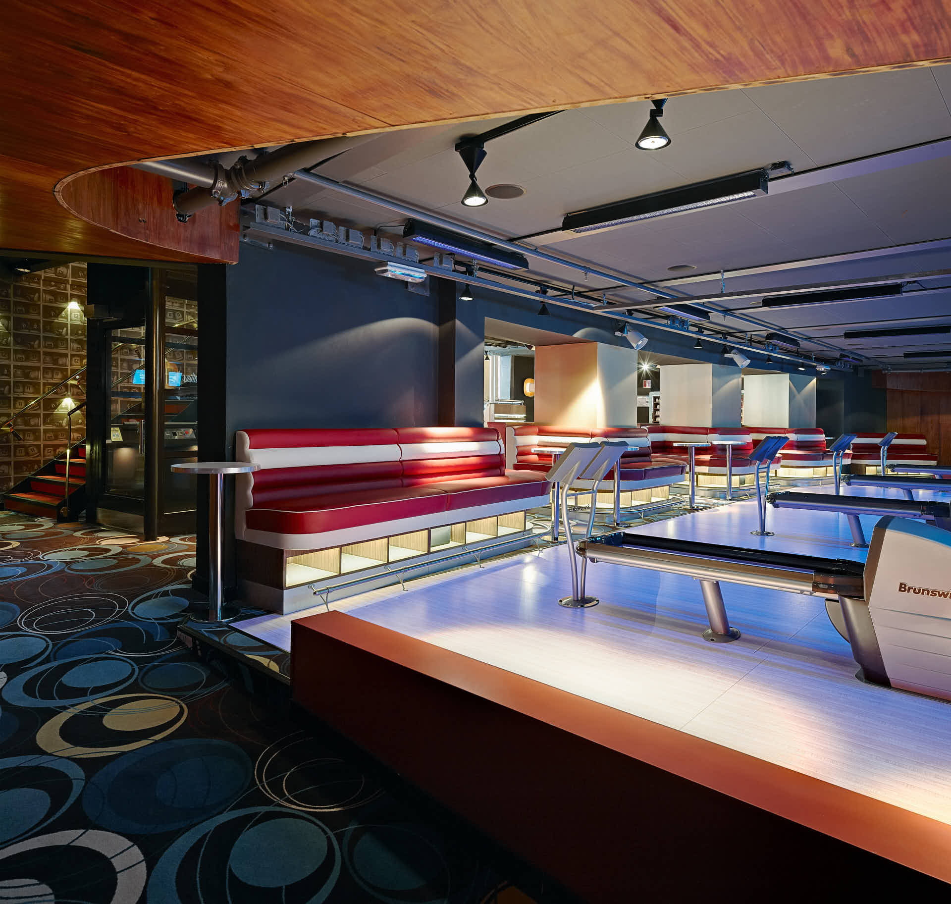 Bowlinghall i Marions Gastro med röda lädersoffor och banor i blått ljus. träpanel i taket intill hallen, i retrodesign. Foto av Martin Ekwall för Co-Pilot.
