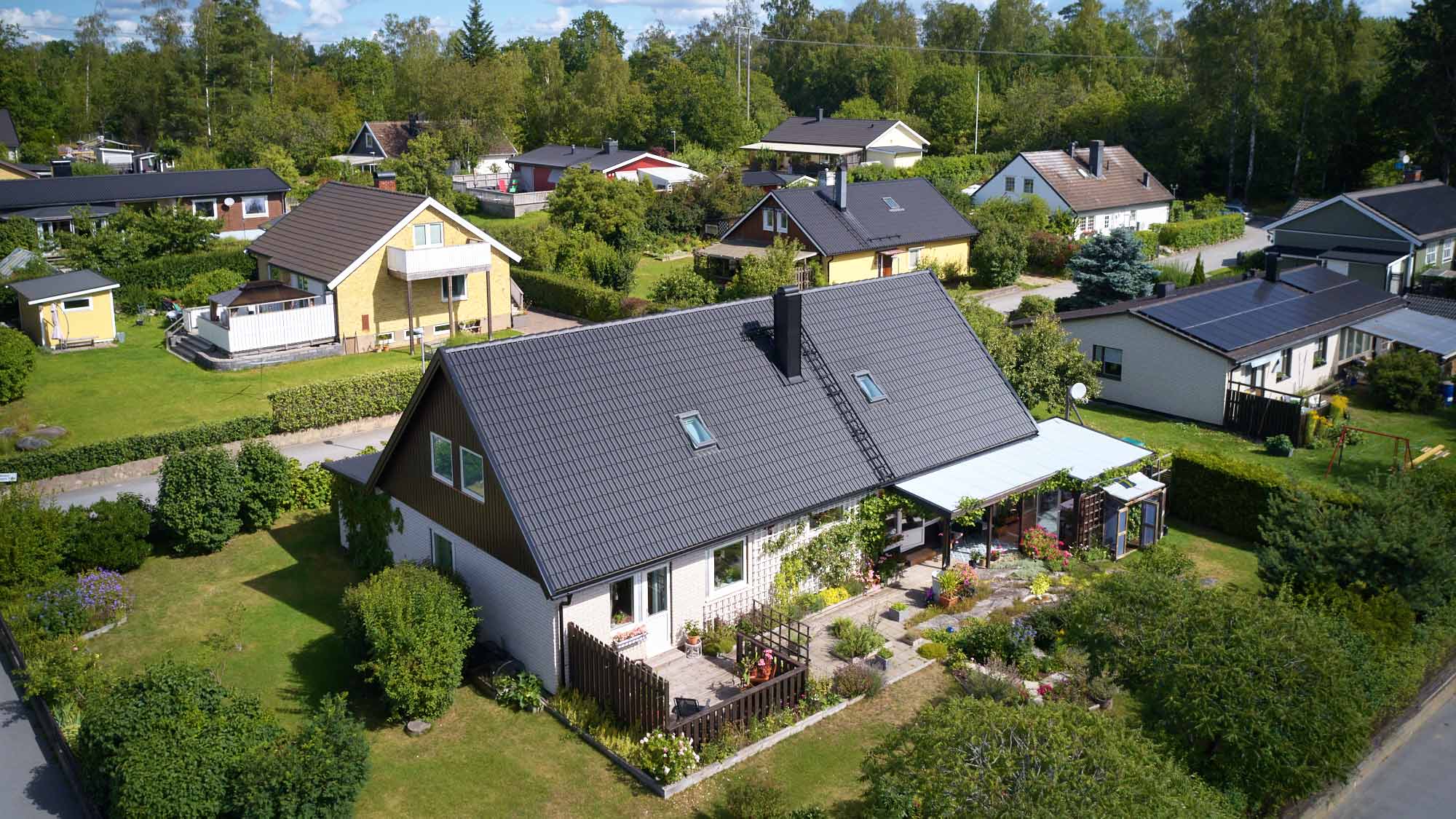 Villa i Osmo med svart betongtegeltak, fotograferad från luften i villakvarter. Arbetet utfört av Villatakspecialisten. Foto Martin Ekwall.