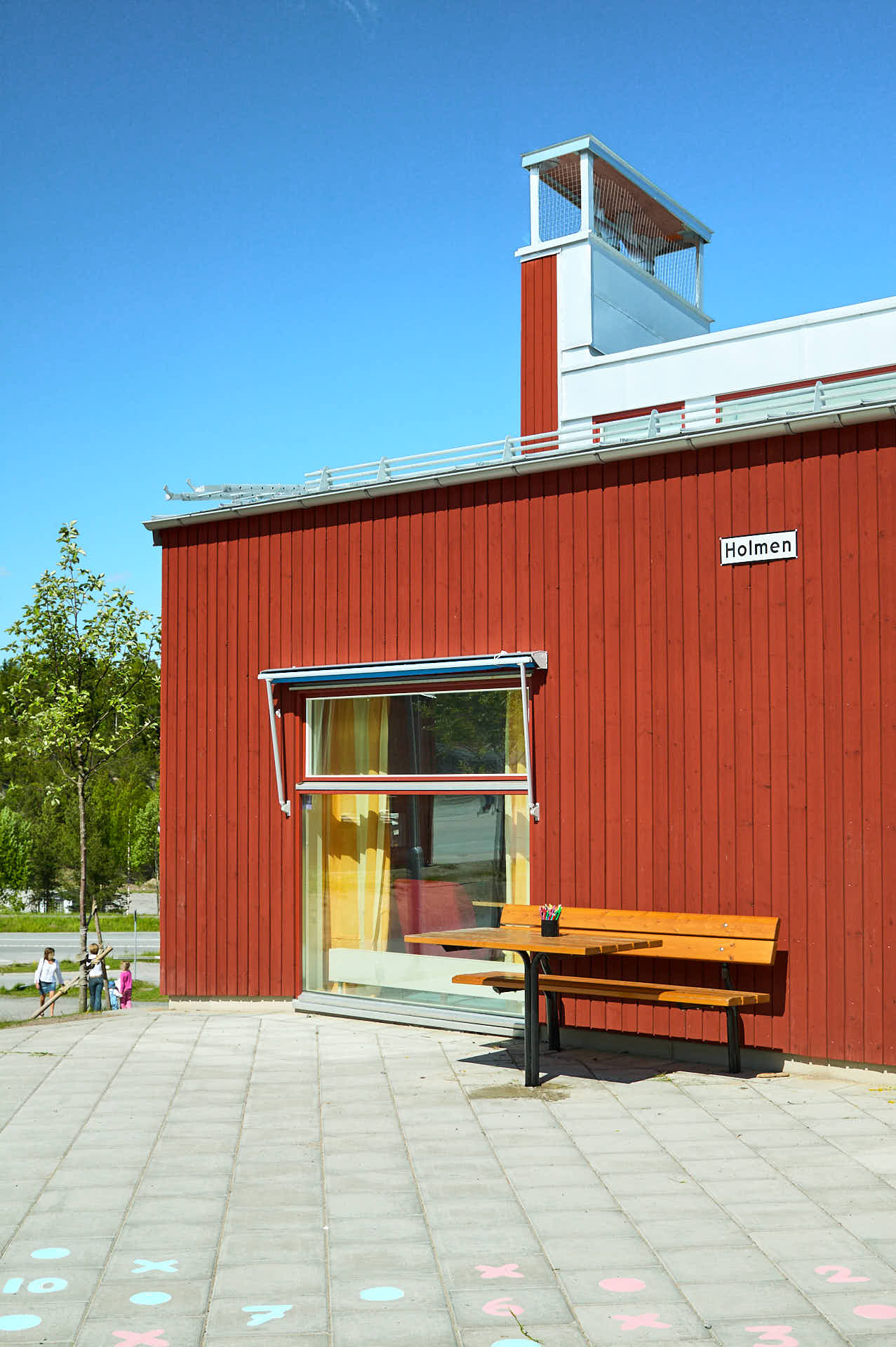 Stort fönster från golv till tak på Brunns skola med fasad i faluröd träpanel. Värmdö i Stockholm ritad av White Arkitekter och fotograferad av Martin Ekwall..