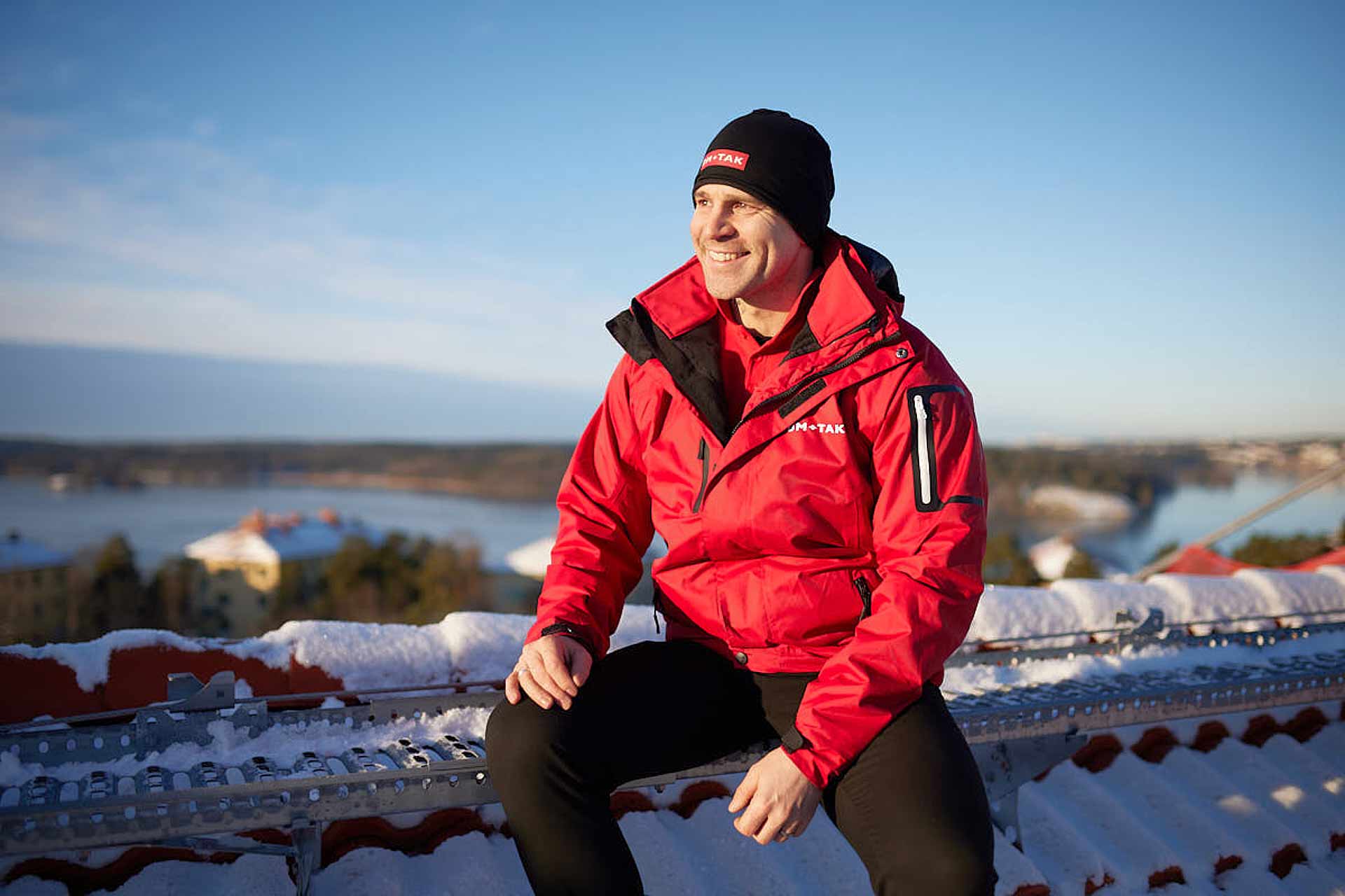 Porträtt av VD i vinterkläder på takbrygga på snötäckt tak i solljus. Foto Martin Ekwall.