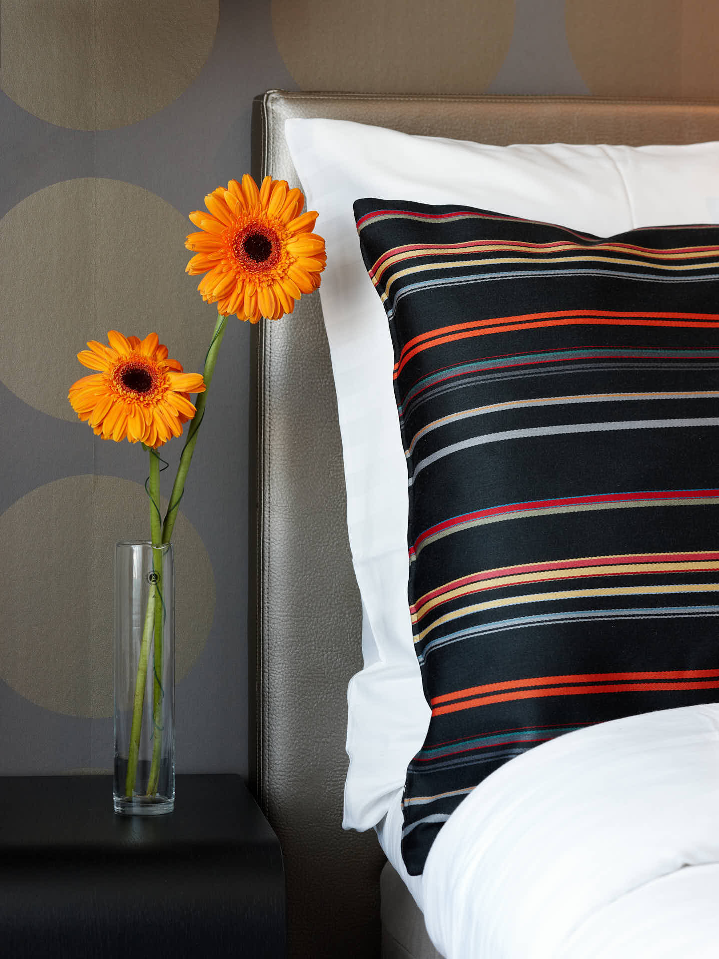 Solna Park Inn, hotellsvit i svart, brun och guldfärger. Detalj av säng, kudde och blomma. Foto Martin Ekwall