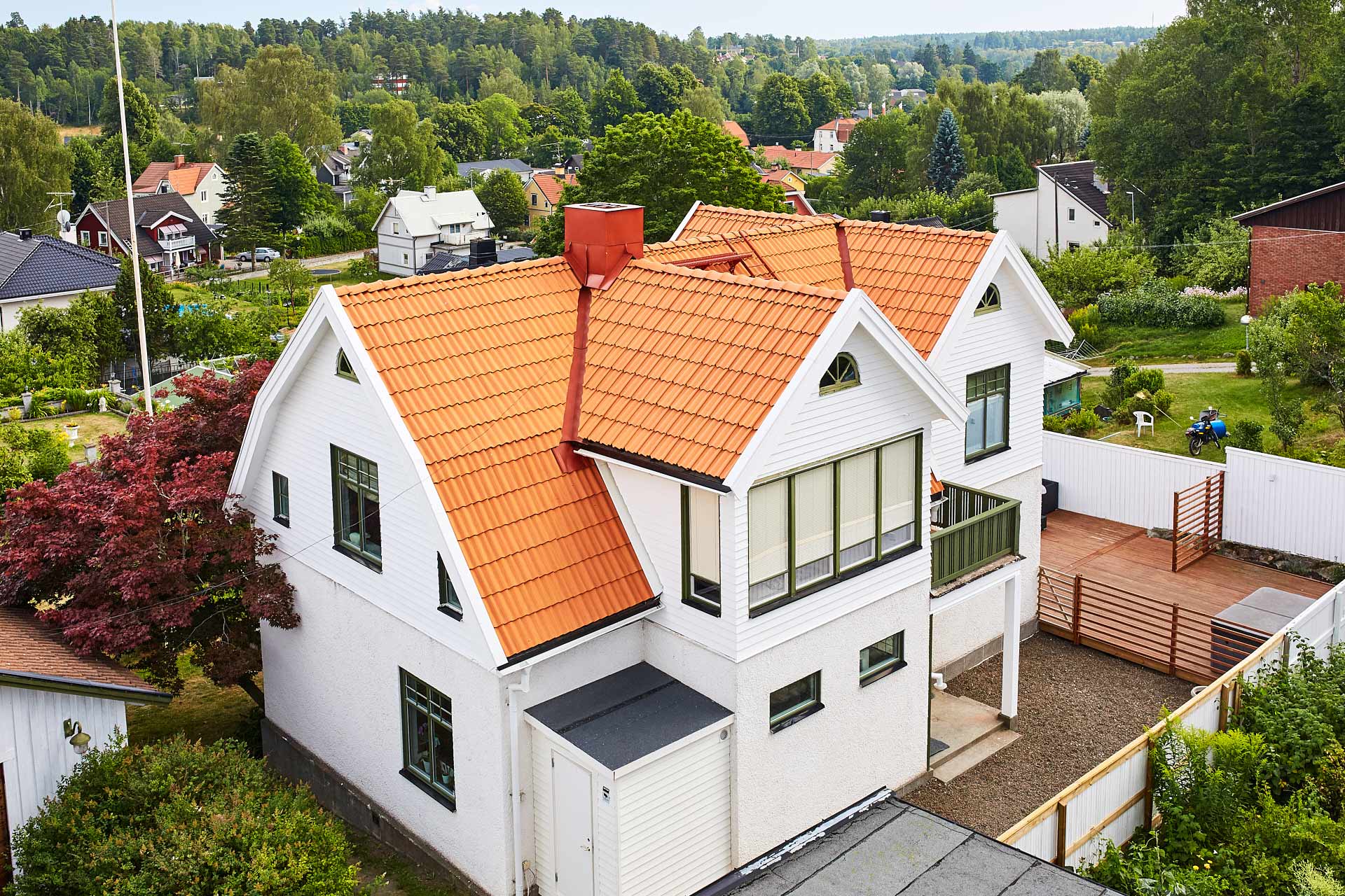 Takarbete utfört utfört av Villatakspecialisten. Vit villa i Tumba med rött lertegeltak, plåtdetaljer, fotograferad från luften. Foto Martin Ekwall.