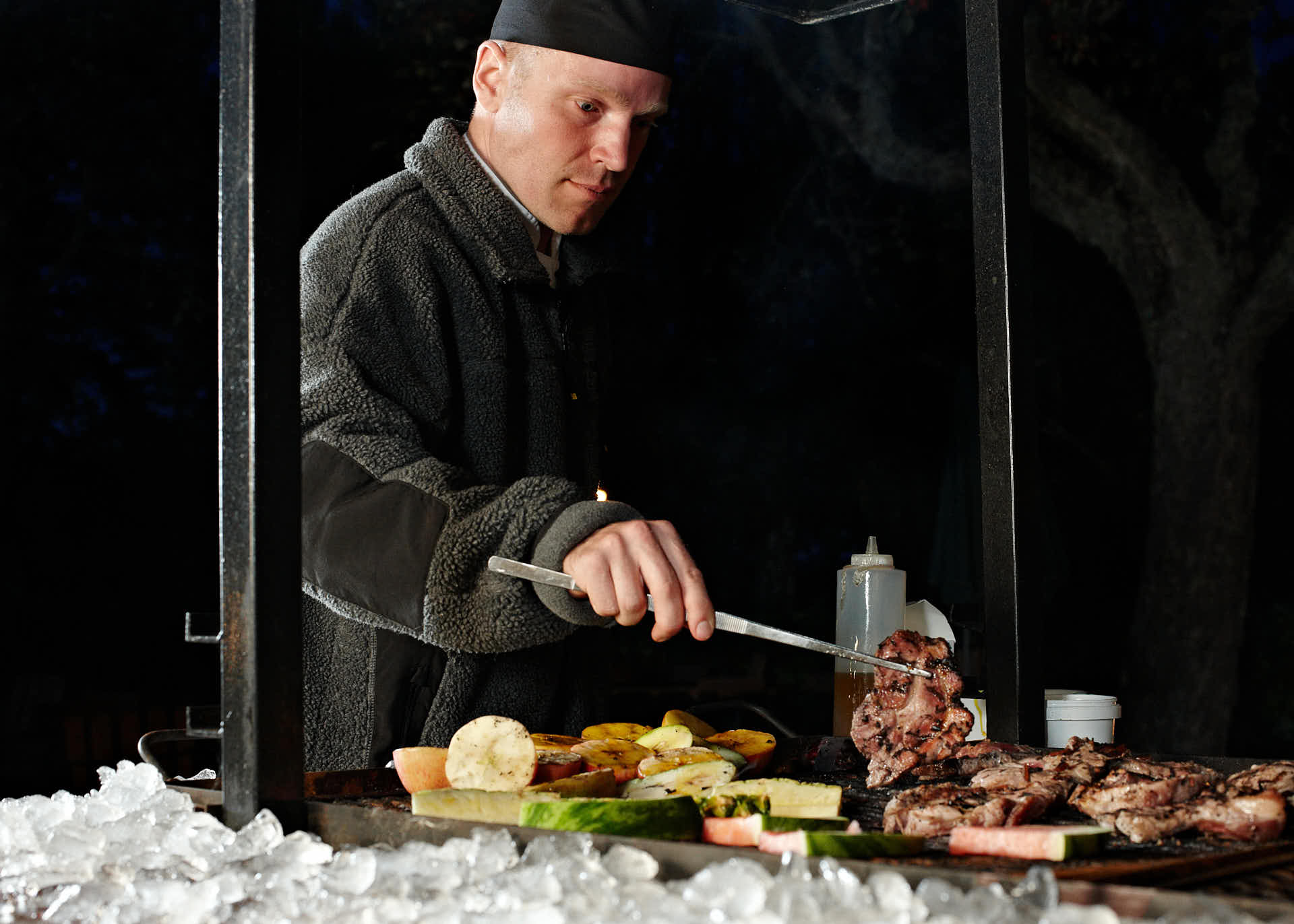 Grillkväll på Gällöfsta Herrgård i tema is och eld, kocken vänder på grillade t-benstekar. Foto Martin Ekwall