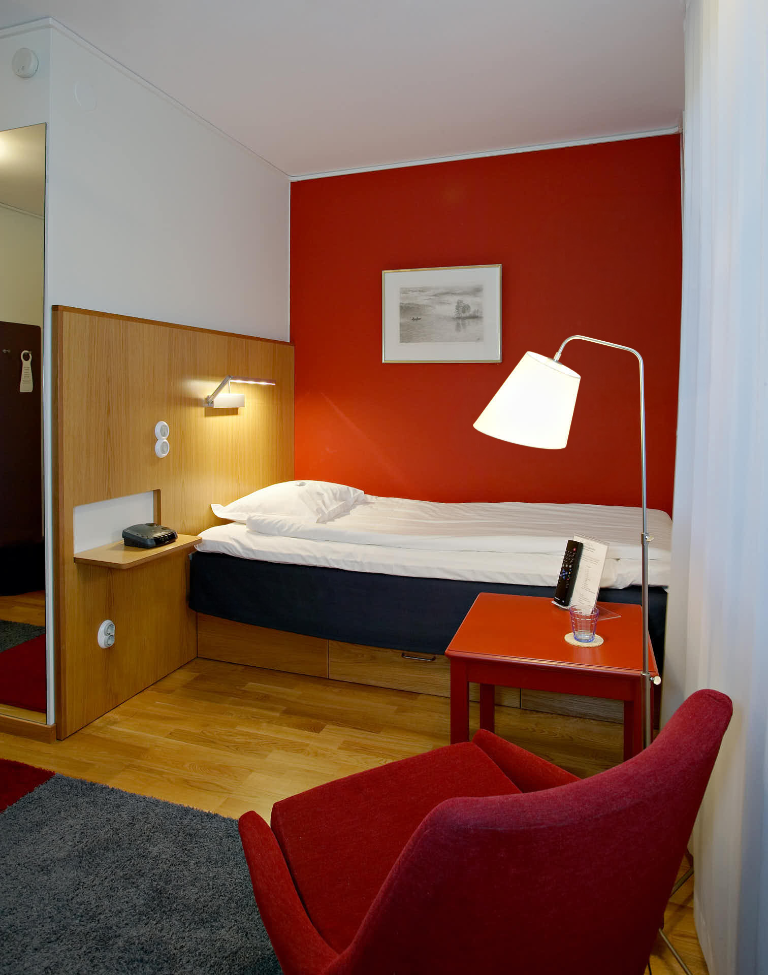 Gällöfsta Herrgård, litet hotellrum enbäddssäng i kvällsljus med fåtölj i förgrunden. Foto Martin Ekwall
