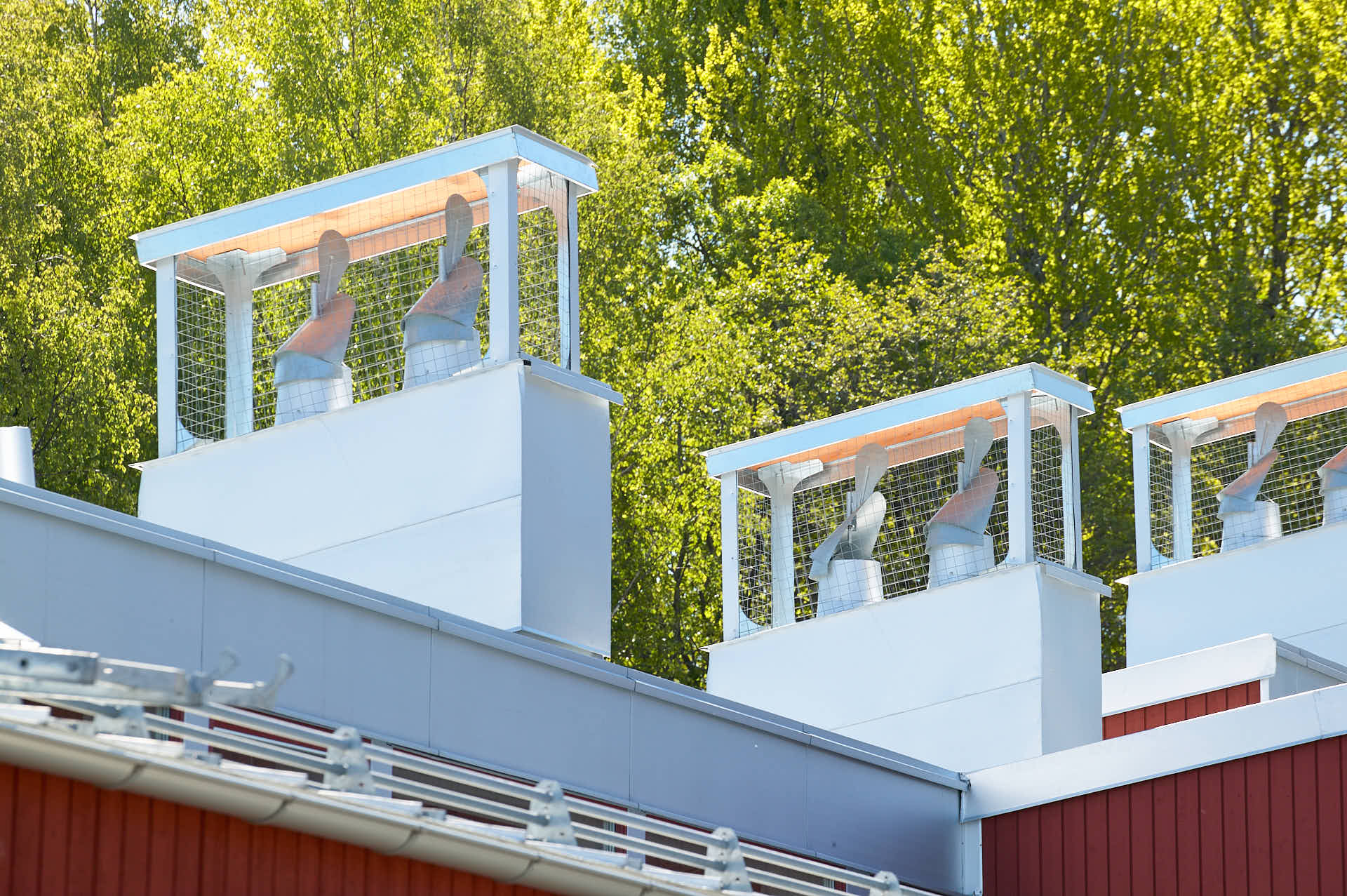 Takvy av Brunns skola med självventilation på taket syns ventilationshuvarna i zinkfärgat plåtarbete. Belägen vid grönområde i Värmdö, Stockholm. Ritad av White Arkitekter och foto av Martin Ekwall..